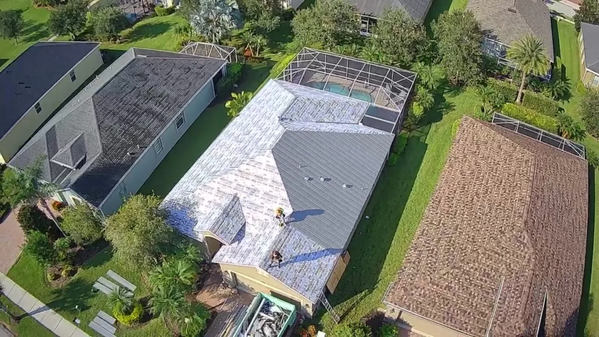 Aerial view of residential roof replacement in Melbourne Florida with synthetic underlayment and metal roofing installation by local roofing contractor.